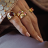 Close-up of a hand wearing gold rings with gemstones on a blurred background
