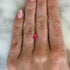 Hand with a pink spinel stone on a textured white background