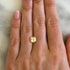 Hand modeling a yellow sapphire gemstone on a neutral background