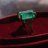 Ring with a green gemstone on a red cushion