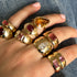 Hand wearing multiple gold rings with gemstones on a denim background