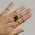 A gold ring with a large mint green tourmaline gemstone set in a rectangular cut on a hand