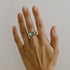 A gold ring with a large mint green tourmaline gemstone set in a rectangular cut on a finger