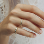 Close-up of a hand wearing two gold rings on a light background