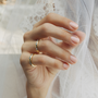 Hand wearing two gold rings with a soft, blurred background