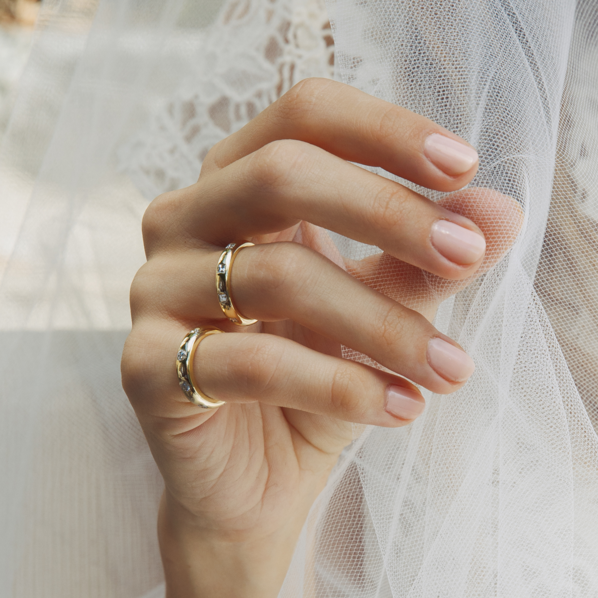 Hand wearing two gold rings with a soft, blurred background