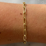 Gold chain bracelet on a wrist against a marble background