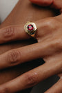 Gold ring with a red gemstone on a person's finger