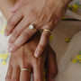 Close-up of two hands with gold rings on a floral fabric background