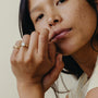Close-up of a woman with a gold ring on her finger against a neutral background