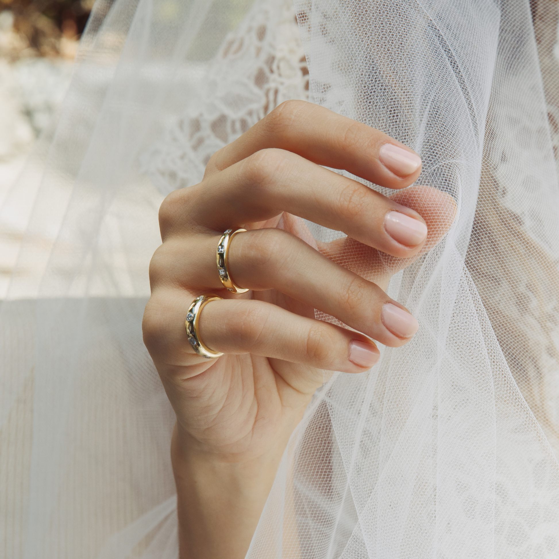 Close-up of a hand wearing two gold rings with a soft focus background