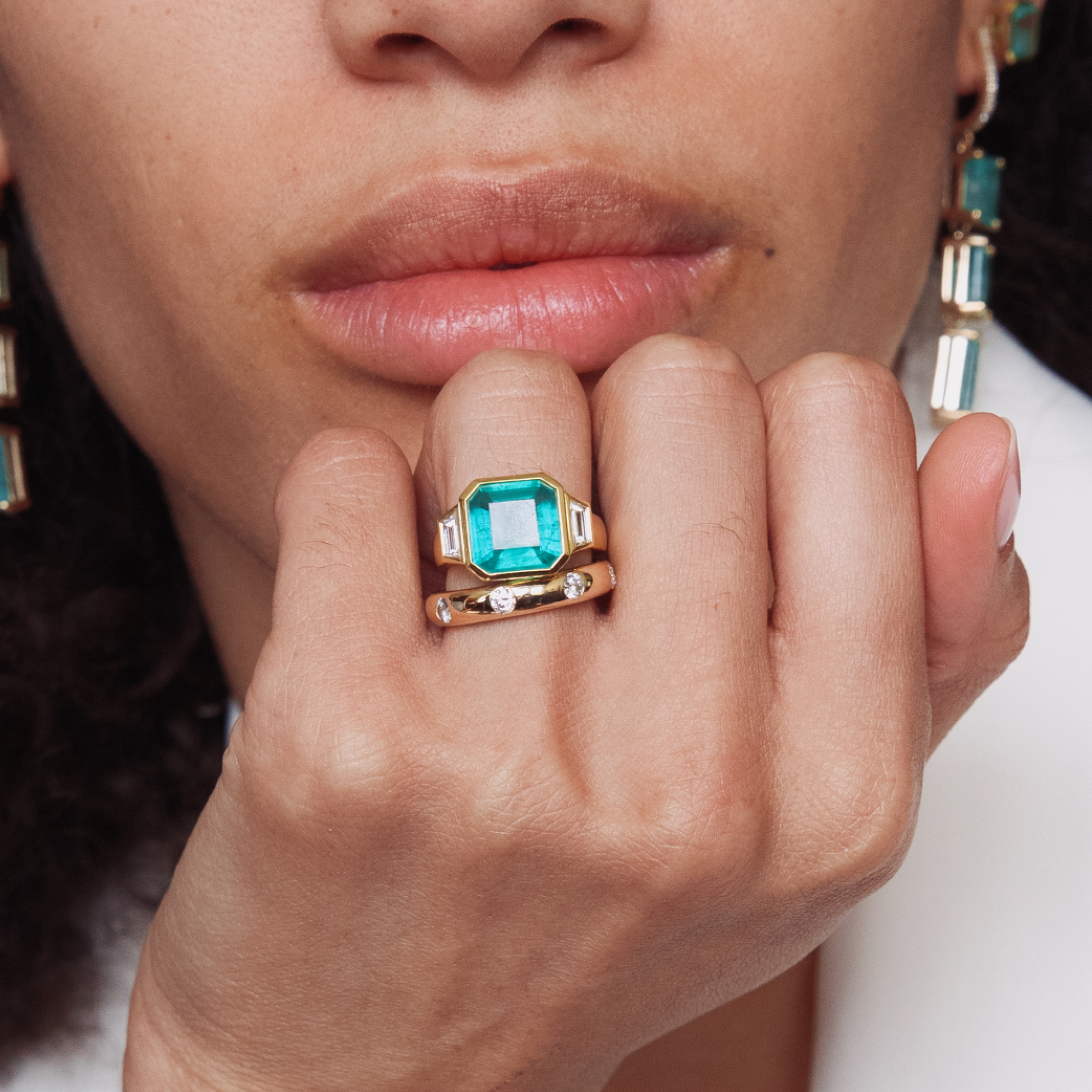Close-up of a hand wearing a green gemstone ring with a blurred background