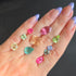 Hand holding various small colored gemstones against a dark background