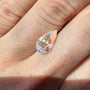Teardrop-shaped moonstone gemstone on a person's finger