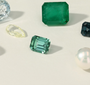 Collection of green gemstones and a pearl on a light background